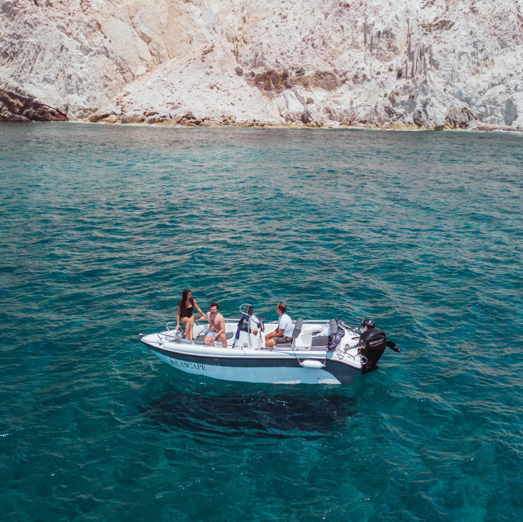 Private boat tour near White Beach Santorini with Seascape Santorini Boat Rentals– group enjoying a luxury cruise on clear turquoise waters with stunning white volcanic cliffs in the background. Perfect for exclusive Santorini sea excursions and private cruising experiences.